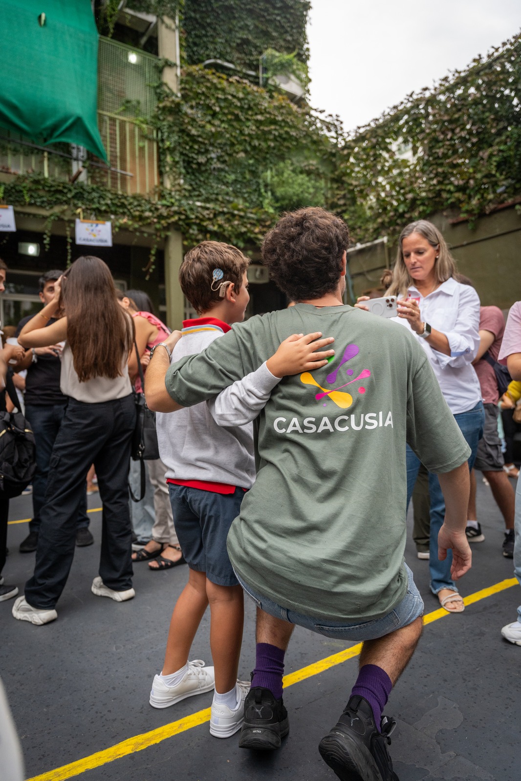 Lucas con remera CASACUSIA abrazando a un nene con audífono